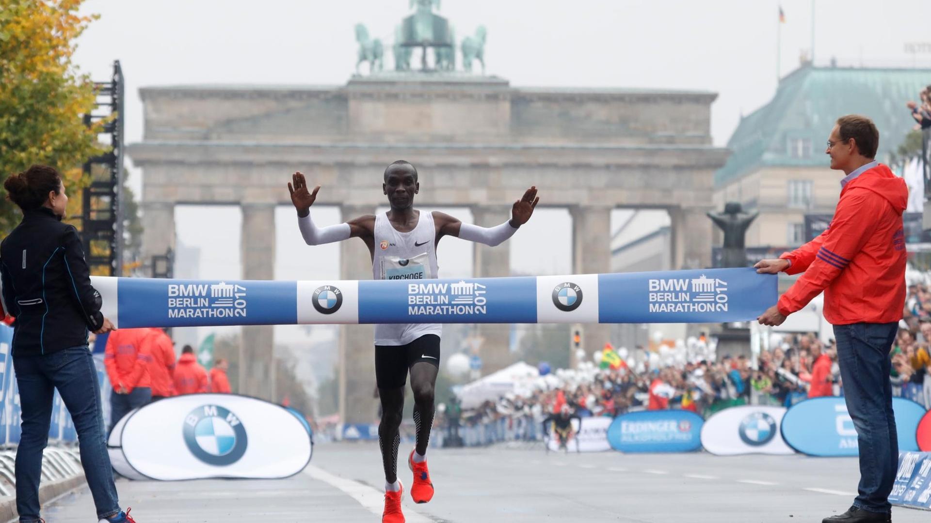 Der Kenianer Eliud Kipchoge läuft beim Berlin-Marathon ins Ziel. Im Hintergrund ist das Brandenburger Tor zu sehen.