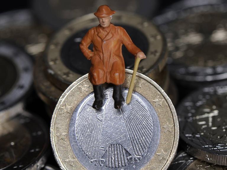 Eine Figur eines älteren Mannes sitzt auf einer Euro-Münze.