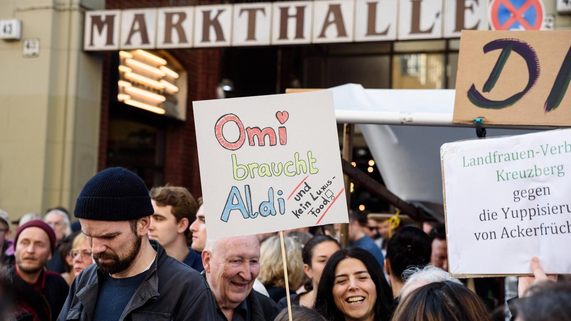 Eine Frau hält ein Schild hoch, auf dem steht: "Omi braucht Aldi".