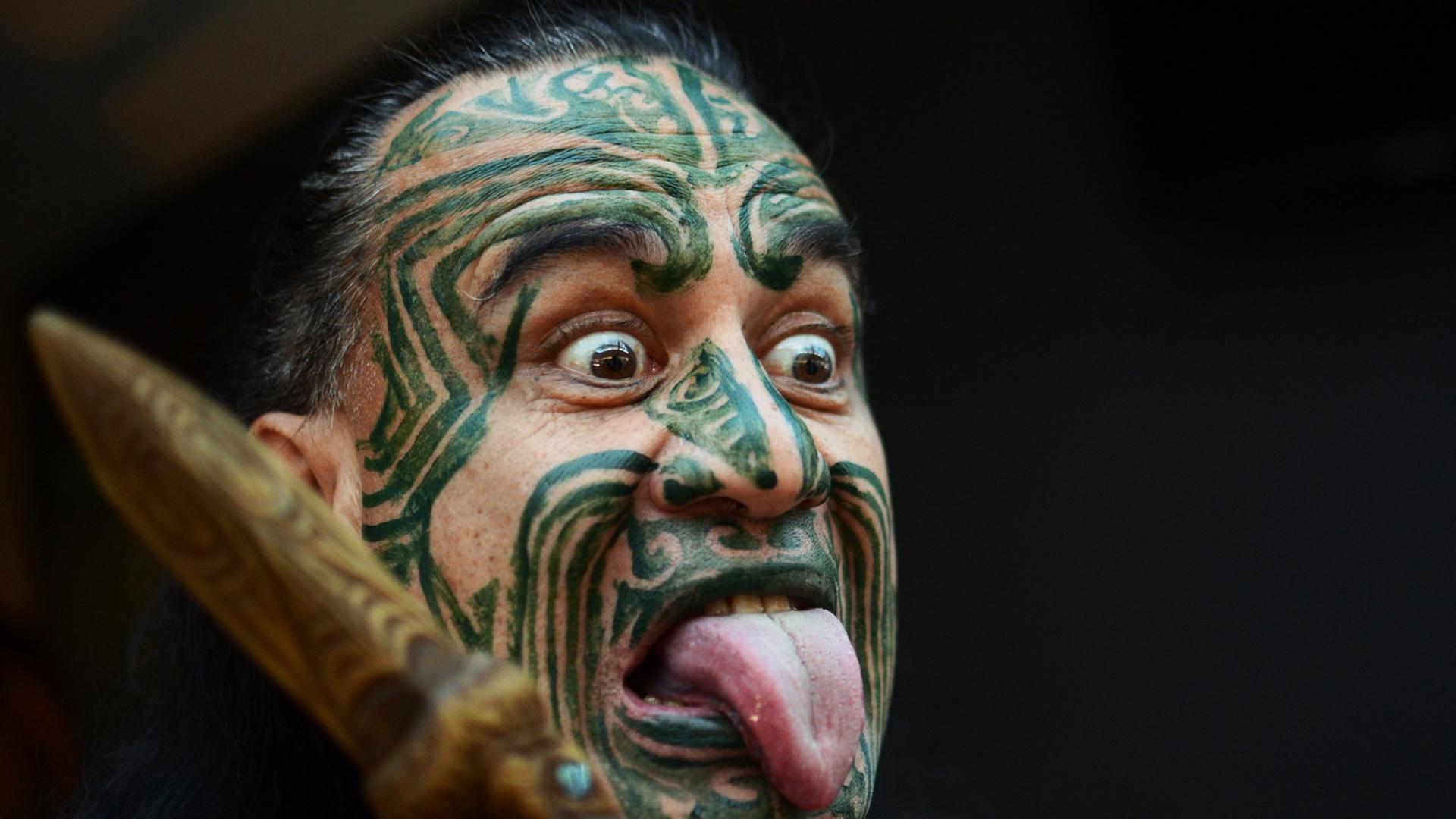 Ein Maori mit einer typischen Gesichtsbemalung und Grimasse.