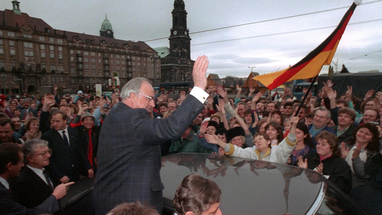 Bundeskanzler Helmut Kohl (CDU) wird am 19. Dezember 1989 anlässlich seines zweitägigen Besuches in der sächsischen Stadt Dresden vor der Kreuzkirche von einer wartenden Menschenmenge stürmisch gefeiert.