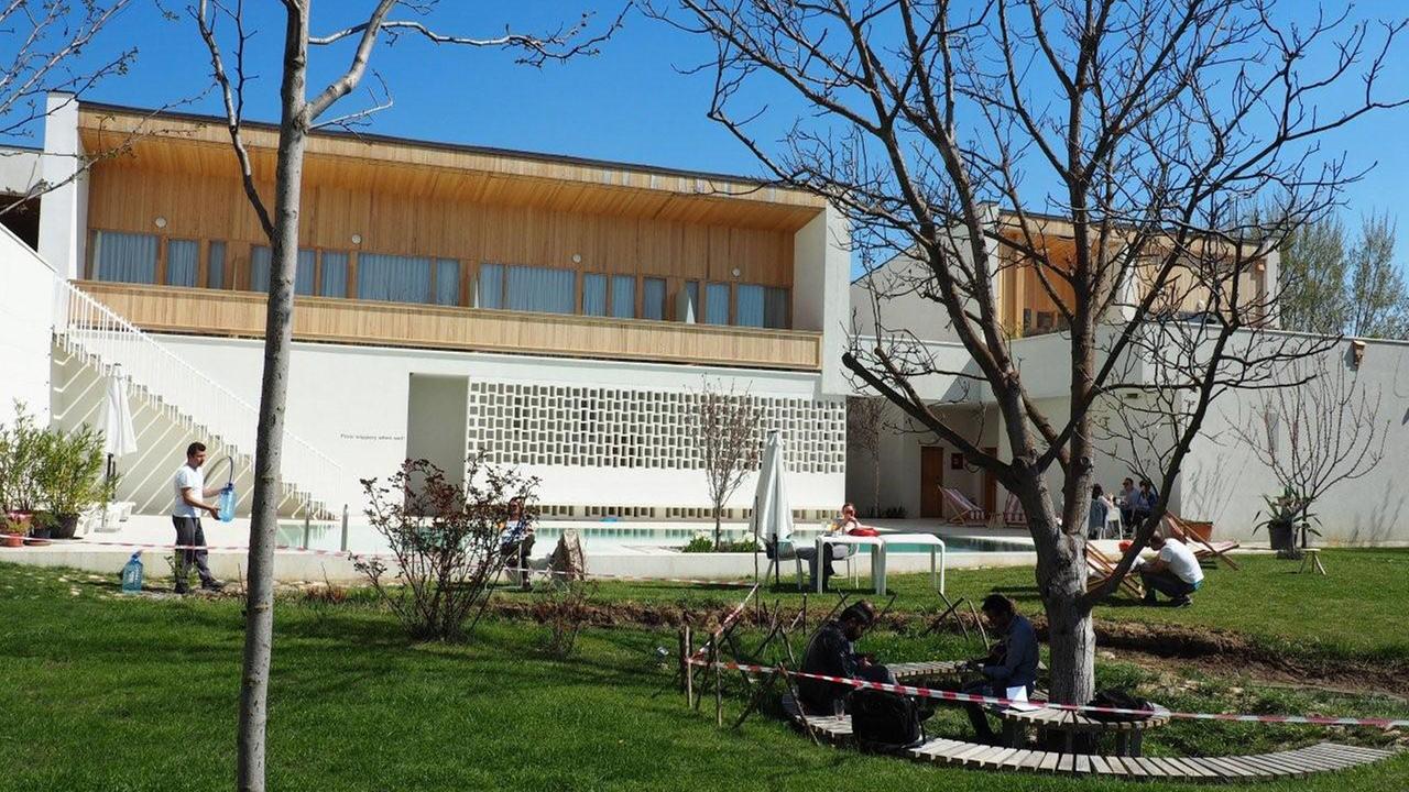 Blick auf das Hotel Gracanica in der kosovarischen Stadt Pristina, im Vordergrund ein Garten mit Pool