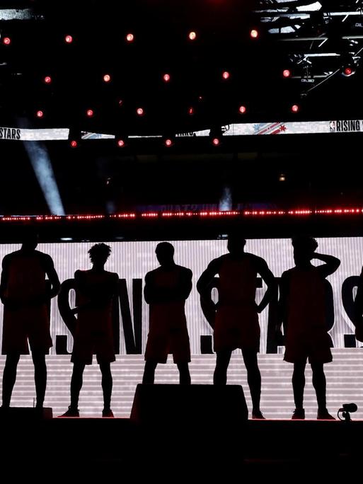 Die Mitglieder des US-Basketballteams sind als Silhouetten nebeneinander stehend zu sehen.