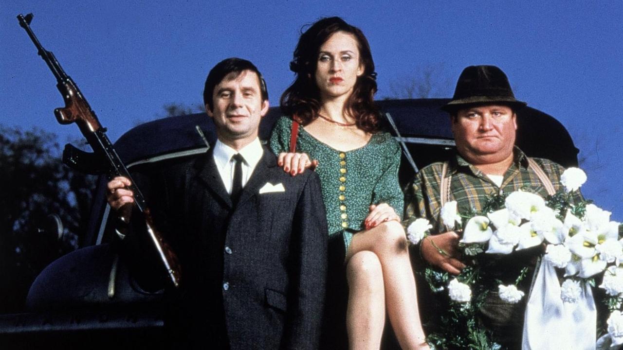 "Wir können auch anders" von 1993 mit den Schauspielern Joachim Krol, Sophie Rois und Horst Krause. Drei Personen vor einem Auto.