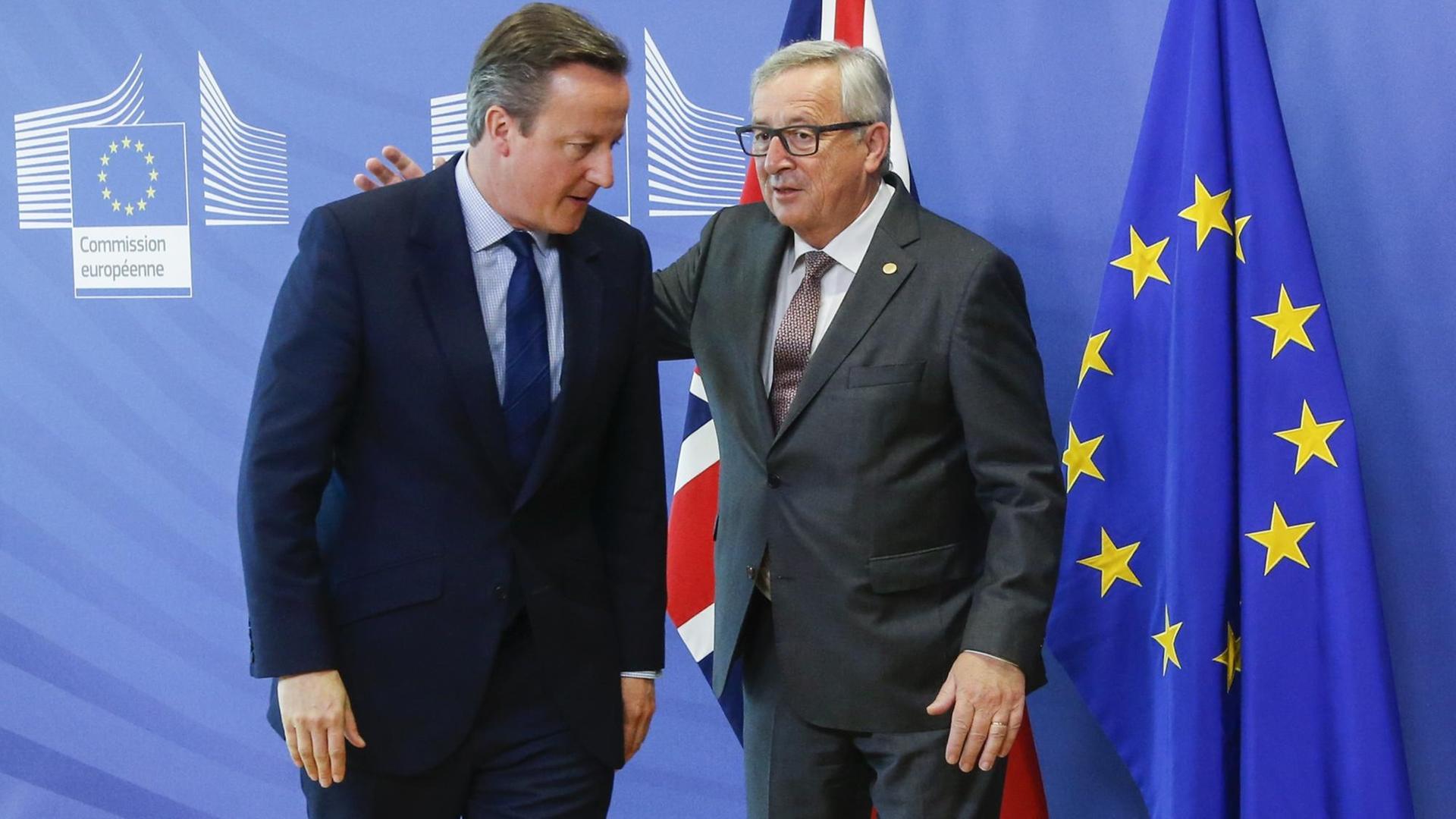 Jean-Claude Juncker klopft David Cameron vor einer EU-Flagge auf den Rücken