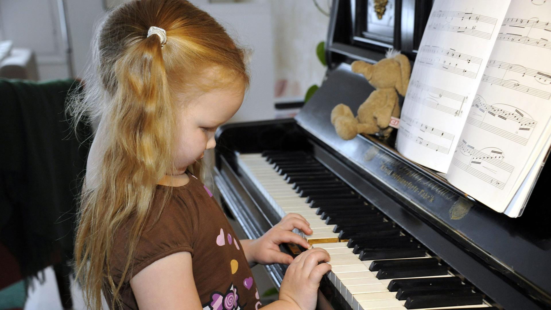 Ein kleines Mädchen spielt auf den Tasten eines Klavieres