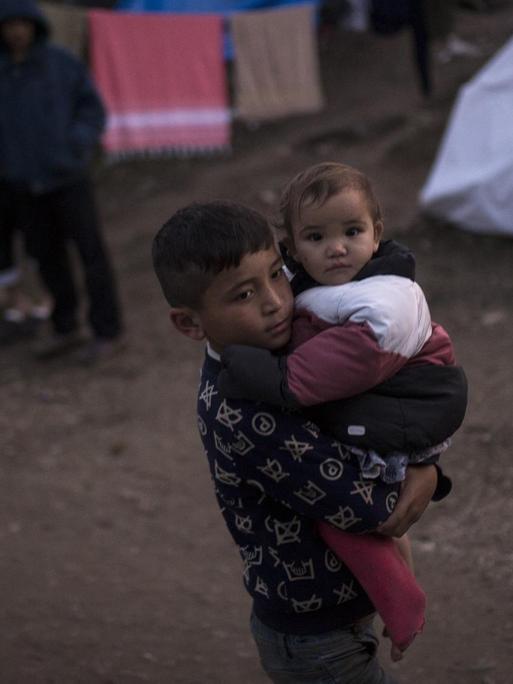 Ein Junge hält im November 2019 im Camp Moria ein Baby auf dem Arm.