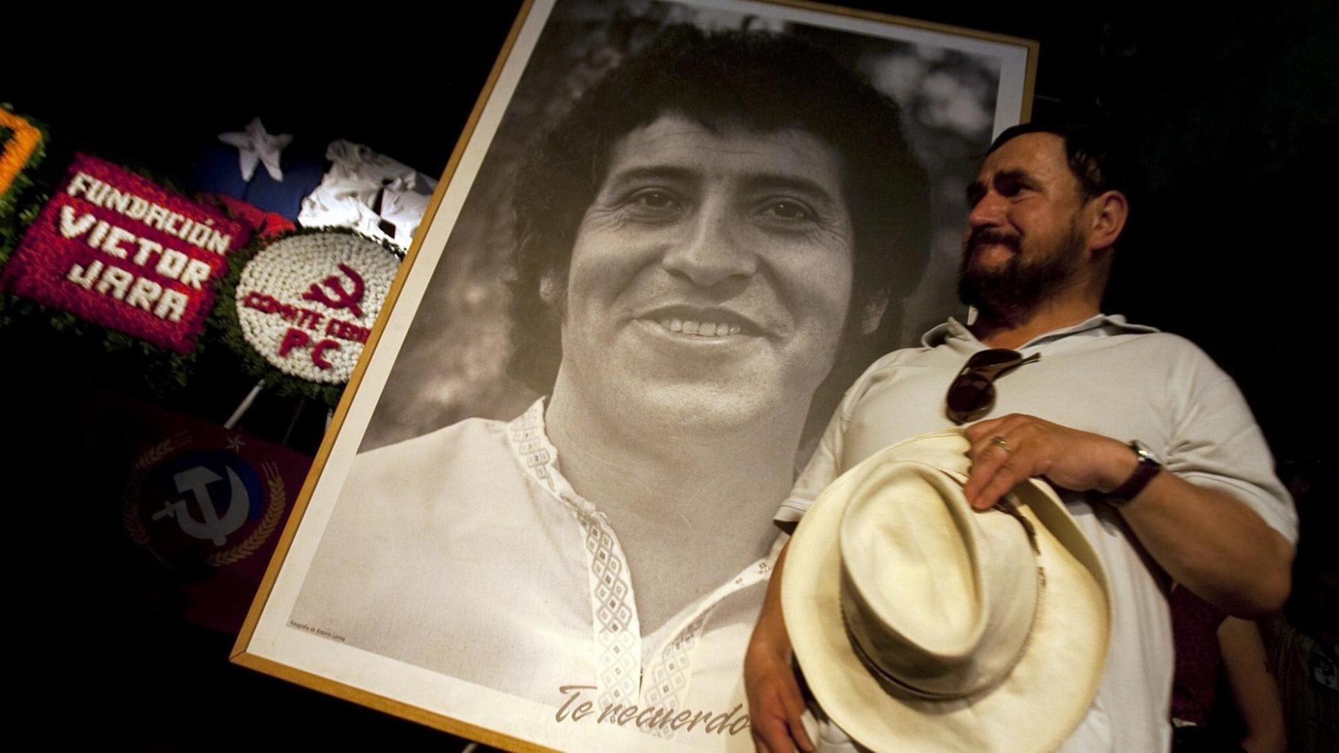 Ein Mann vor einem Schwarz-Weiß-Foto des ermordeten chilenischen Sängers Victor Jara.