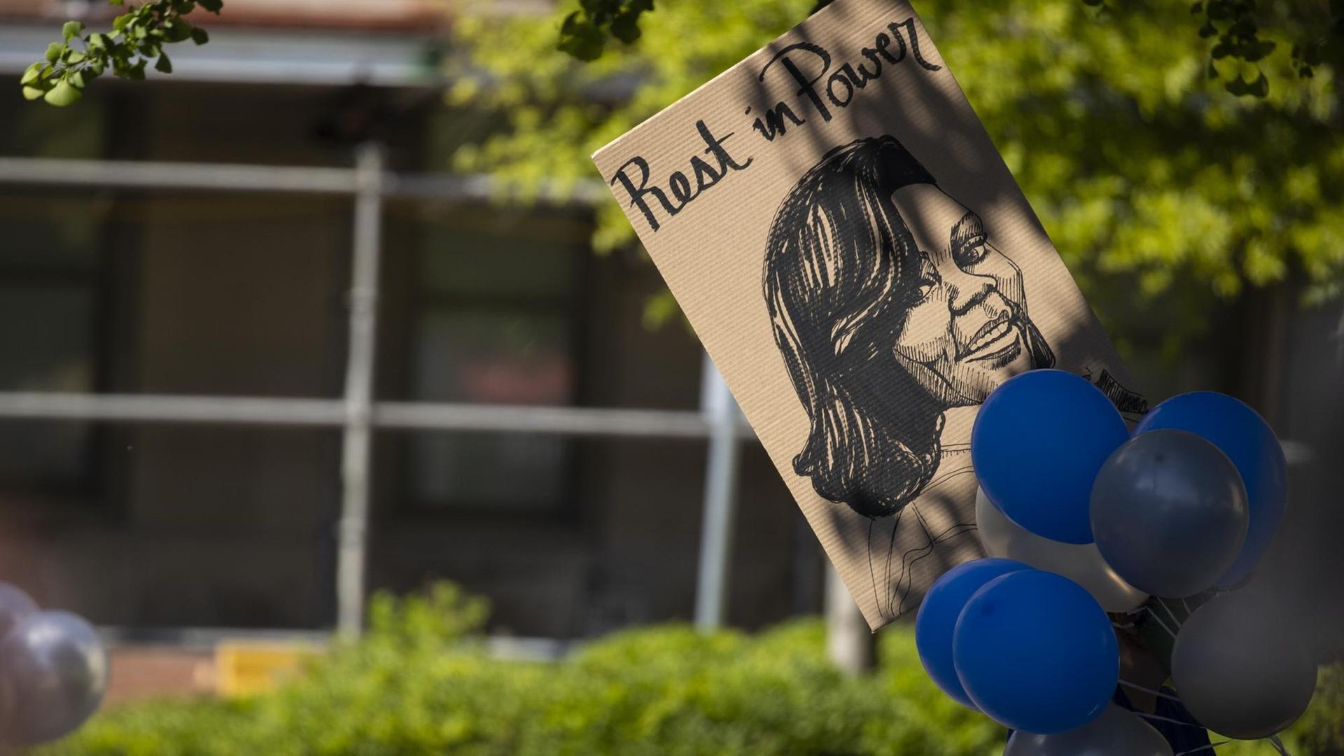 Jemand hält ein Plakat und Luftballons in die Luft, um an Breonna Taylor zu erinnern.