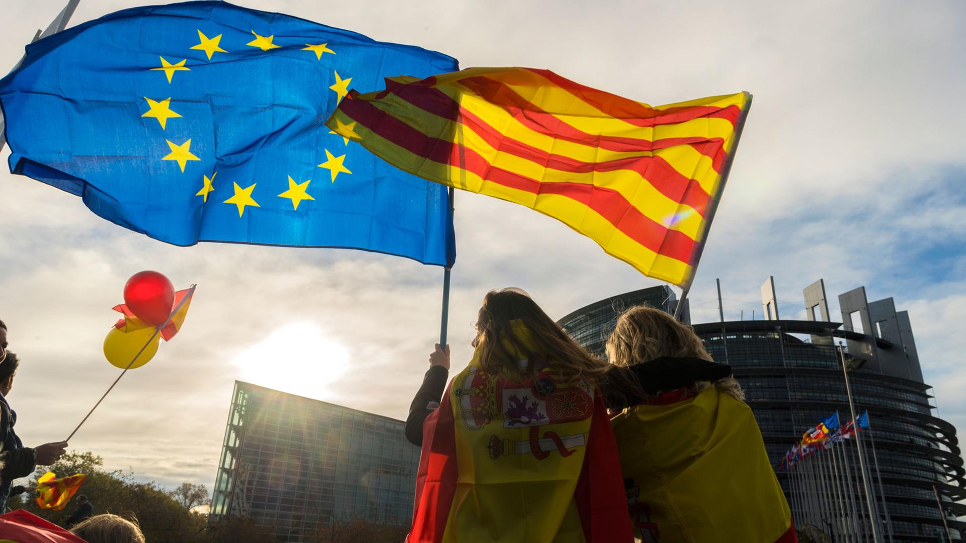 Vor dem Europaparlament in Straßburg demonstrieren Frauen mit einer katalanischen und einer europäischen Flagge in der Hand
