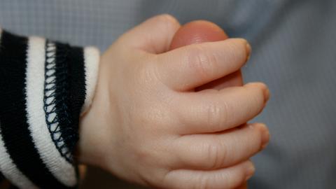 Eine Babyhand umschließt den Finger eines Erwachsenen