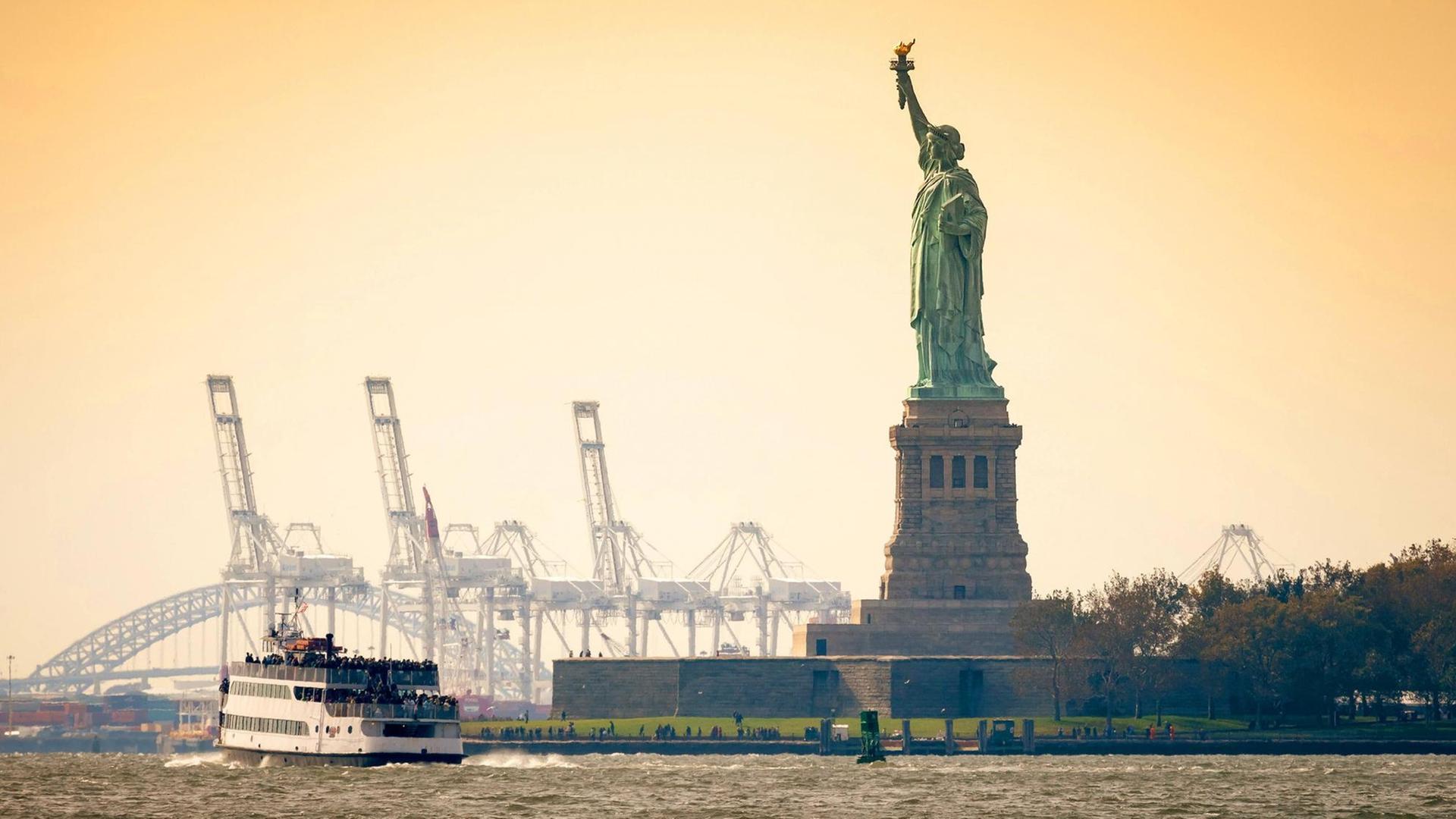 Die Freiheitsstatue auf Liberty Island vor New York mit einem vorbeifahrenden Schiff. Die Freiheitsstatue auf Liberty Island vor New York mit einem vorbeifahrenden Schiff.