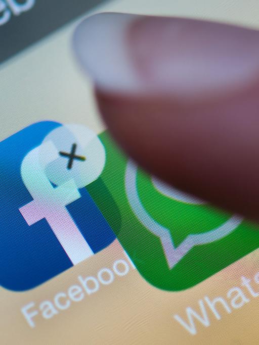Ein Finger verschiebt auf einem Smartphone-Display die Anwendung "WhatsApp" auf die Facebook-App