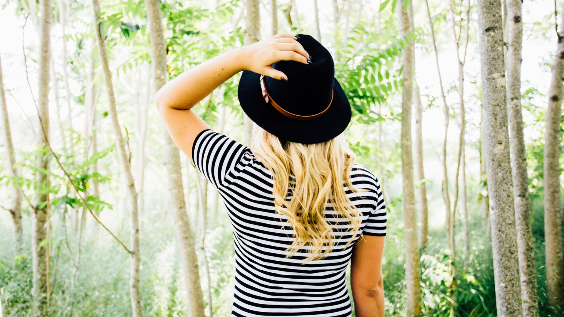 Eine Frau in einem gestreiften Shirt steht in einem Wald.