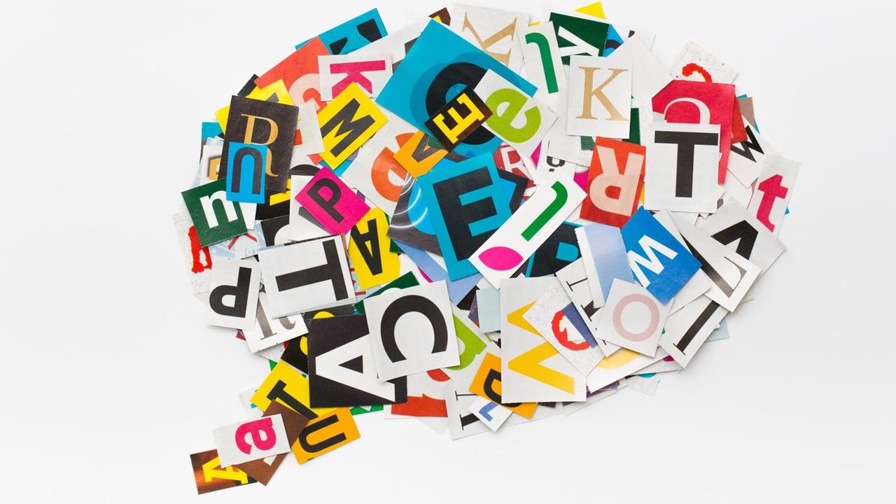 In einer Sprachblase sind ausgeschnittene, bunte Buchstaben völlig durcheinander angeordnet.
