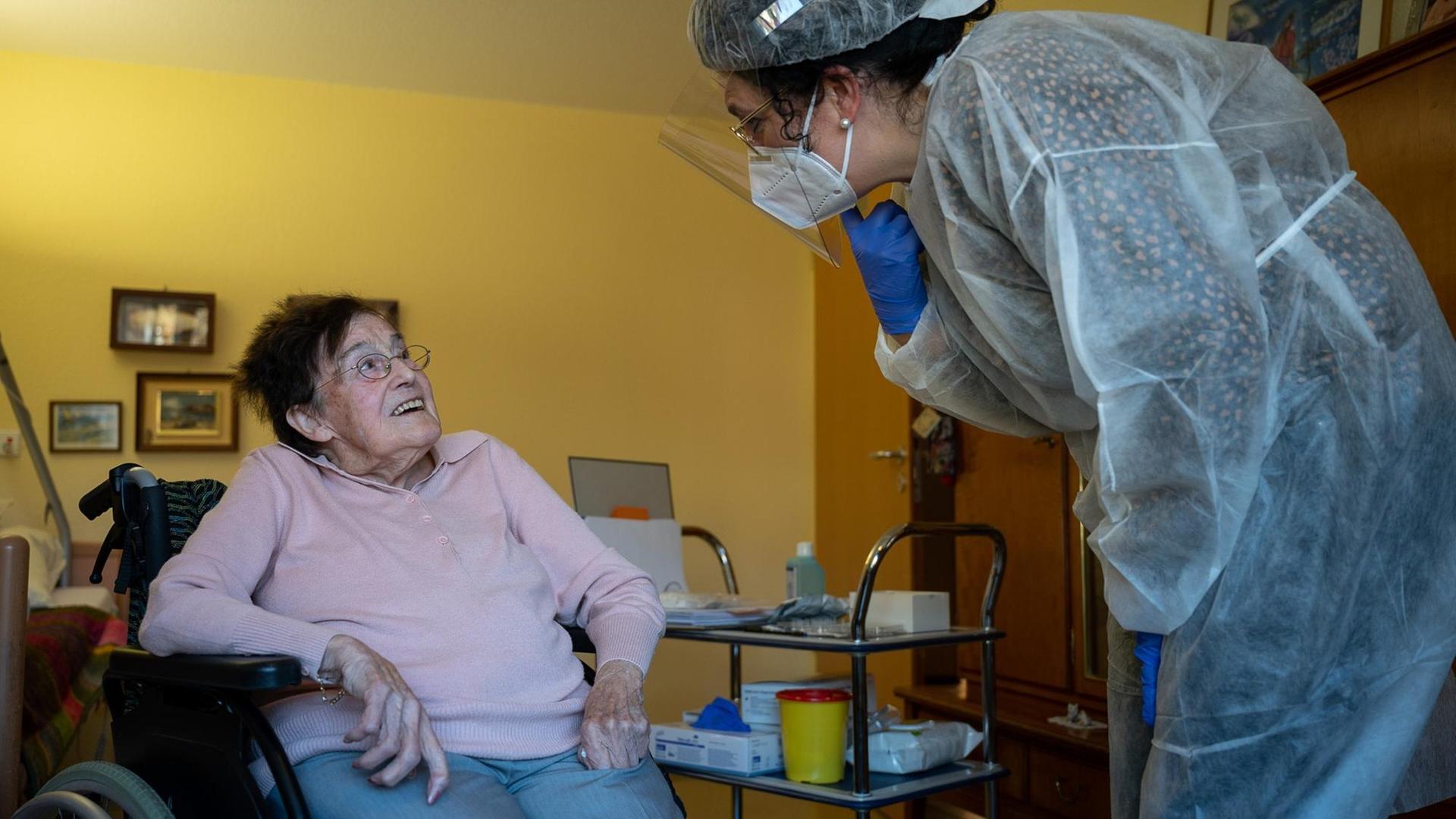 Eine Altenpflegerin spricht im Seniorenheim Pauline-Krone-Heim der Altenhilfe Tübingen vor einem Antigen-Corona-Schnelltest mit einer Bewohnerin.