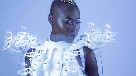 Auf dem Bild ist das futuristische anmutende weiße Kleid der Designerin Anouk Wipprecht zu sehen. Es hat seltsame Sensoren, die sich von ihm abheben.