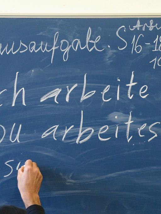 Mohsen Mirzai aus Afghanistan konjugiert während einer Unterrichtseinheit eines Deutschkurses für Flüchtlinge am 09.12.2013 in Schwäbisch Gmünd (Baden-Württemberg) an einer Tafel das Verb "arbeiten".