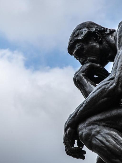 Die Plastik "Der Denker" ("Le Penseur") des Bildhauers Auguste Rodin ist vor einem wolkenverhangenen Himmel zu sehen.