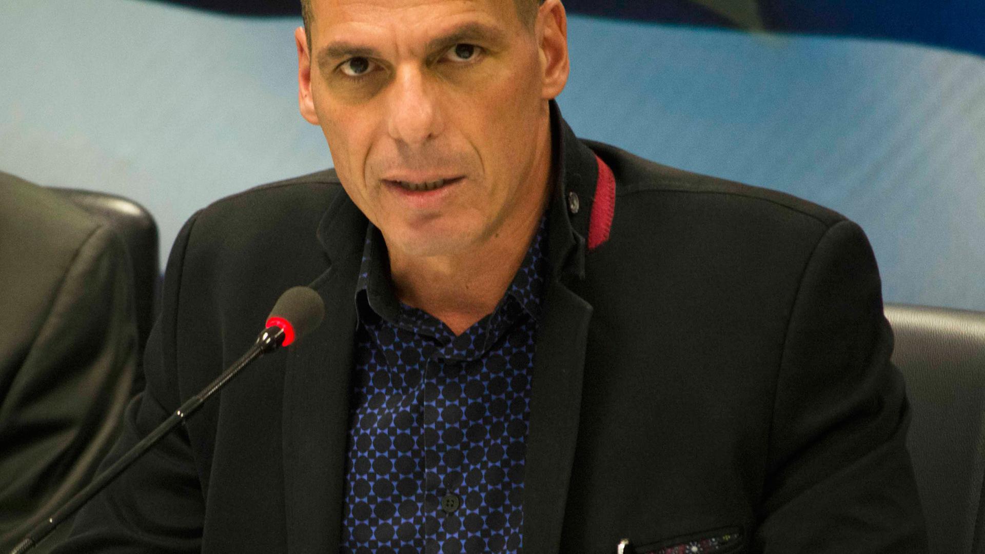 Yanis Varoufakis spricht an einem Mikrofon.