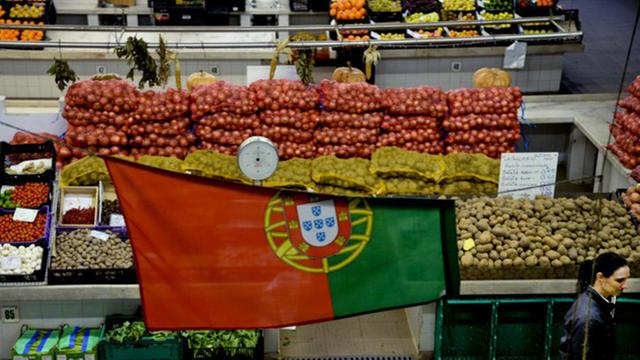 Ein Kunde geht unter einer portugiesischen Fahne hindurch, die am Markt nahe dem Saldanha-Platz in Lissabon aufgespannt ist.