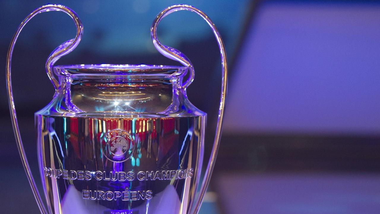 Das Bild zeigt den oberen Teil des Pokals der Champions League. Er und der Hintergrund sind lilafarben angestrahlt.