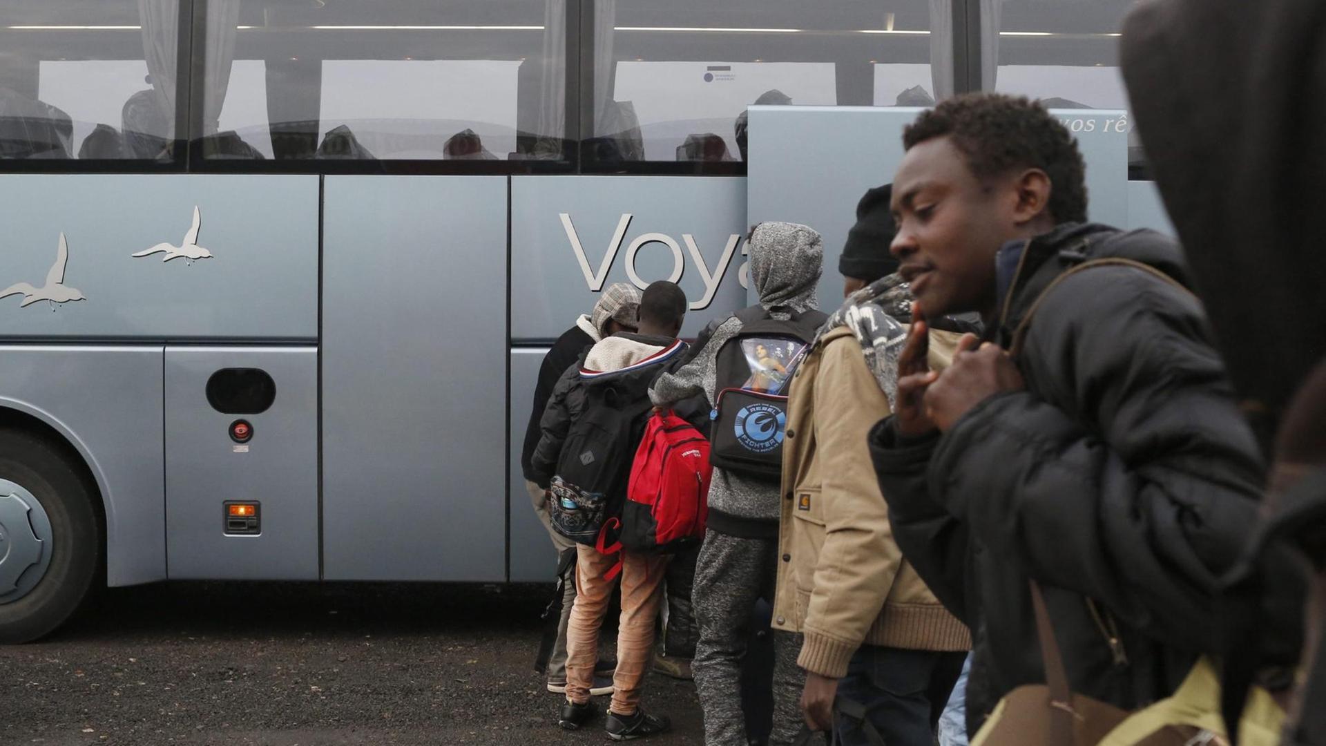 Migranten stehen in einer Schlange vor einem Bus und warten auf ihre Evakuierung kurz bevor die Räumung des Lagers in Calais beginnt.