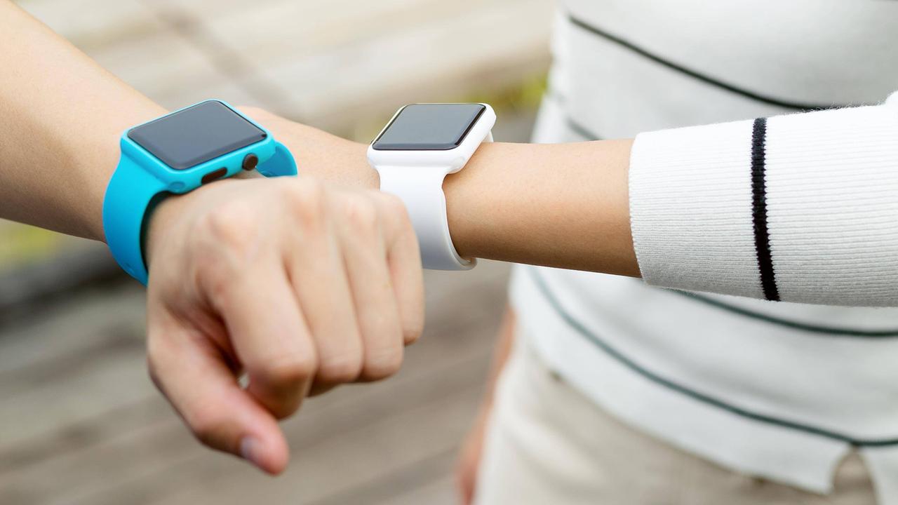 Eine blaue und eine weiße Smartwatch an je einem Handgelenk