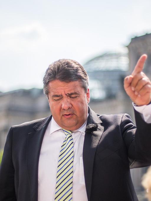 Bundeswirtschaftsminister Sigmar Gabriel (SPD) steht am 27.07.2014 auf der Terrasse des Marie-Elisabeth-Lüders-Hauses in Berlin während des Sommerinterviews für die ARD-Sendung "Bericht aus Berlin" und deutet mit dem Zeigefinger. Im Hintergrund der Reichstag.