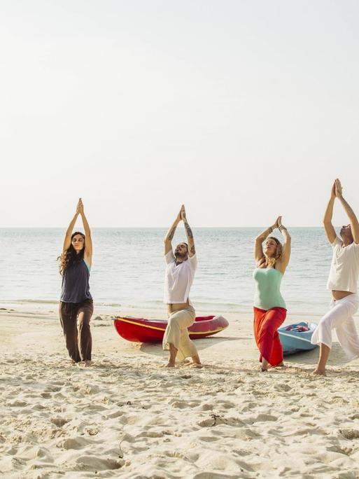 Eine Gruppe Menschen macht Yoga am Strand.
