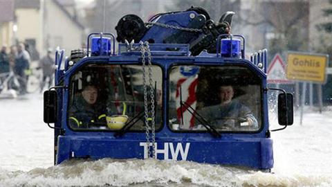 Mitarbeiter des Technischen Hilfswerk fahren in Gohlis bei Pirna, Sachsen, durch eine überflutete Straße.