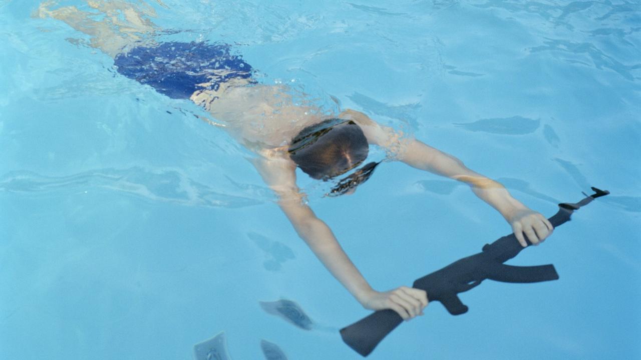 In einem Pool schwimmt ein Kunge mit einer Waffe. 