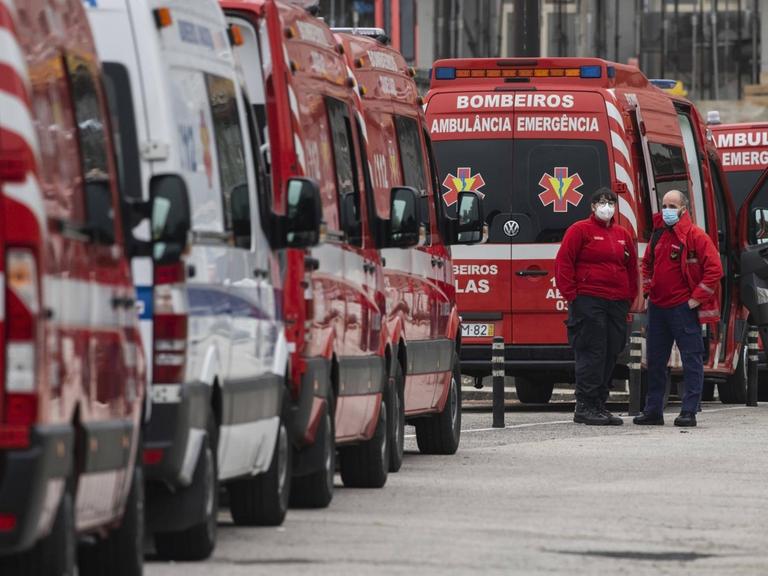 Rote Krankenwagen warten in Portugal vor einem Krankenhaus in einer Schlange.