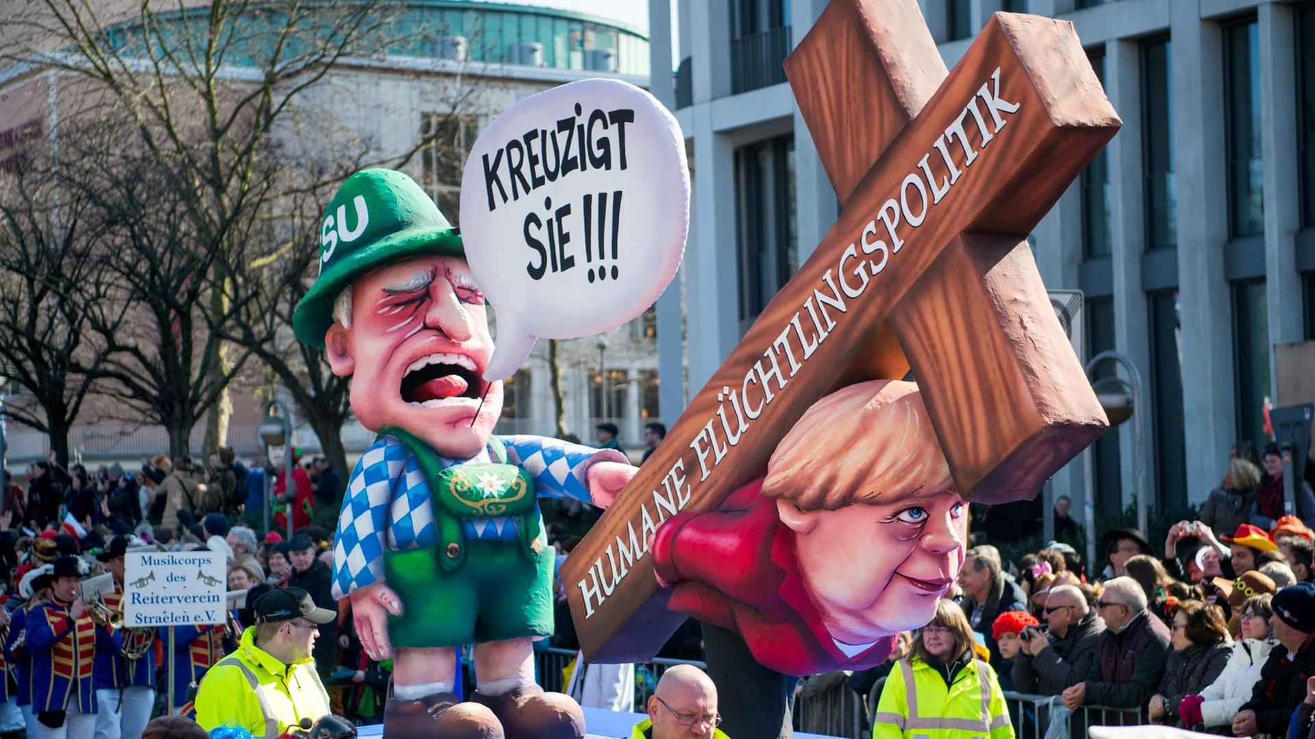 Ein Mottowagen vom Düsseldorfer Umzug: Angela Merkel trägt ein Holzkreuz, das die Aufschrift „Humane Flüchtlingspolitik“ trägt. Hinter ihr steht Horst Seehofer, er ruft „Kreuzigt sie!“. Ein Mottowagen vom Düsseldorfer Umzug: Angela Merkel trägt ein Holzkreuz, das die Aufschrift „Humane Flüchtlingspolitik“ trägt. Hinter ihr steht Horst Seehofer, er ruft „Kreuzigt sie!“.