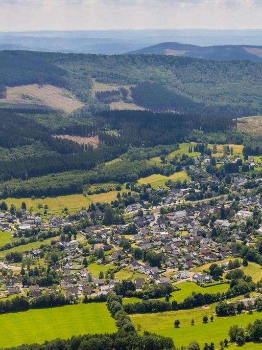 Luftbild des Ortes Wellschen-Ennest. Im Hintergrund liegt eine Hügelkette.