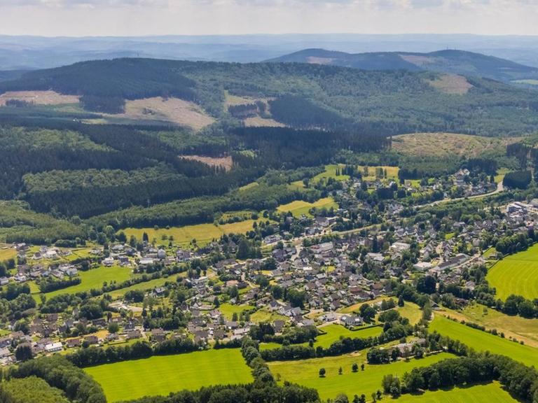 Luftbild des Ortes Wellschen-Ennest. Im Hintergrund liegt eine Hügelkette.