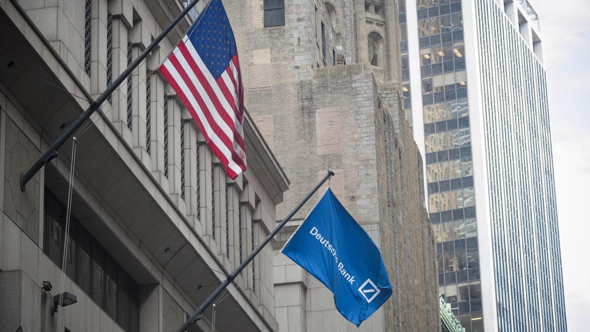 Die US-amerikanische Flagge und eine Flagge mit dem Logo der Deutschen Bank an dem Hauptgeschäftsgebäude der Deutschen Bank auf der Wall Street in New York.