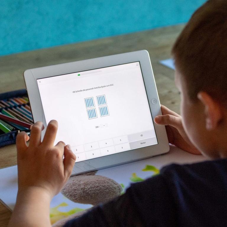 Eine Junge löst zu Hause seine Schulaufgaben am Ipad, Tablet PC