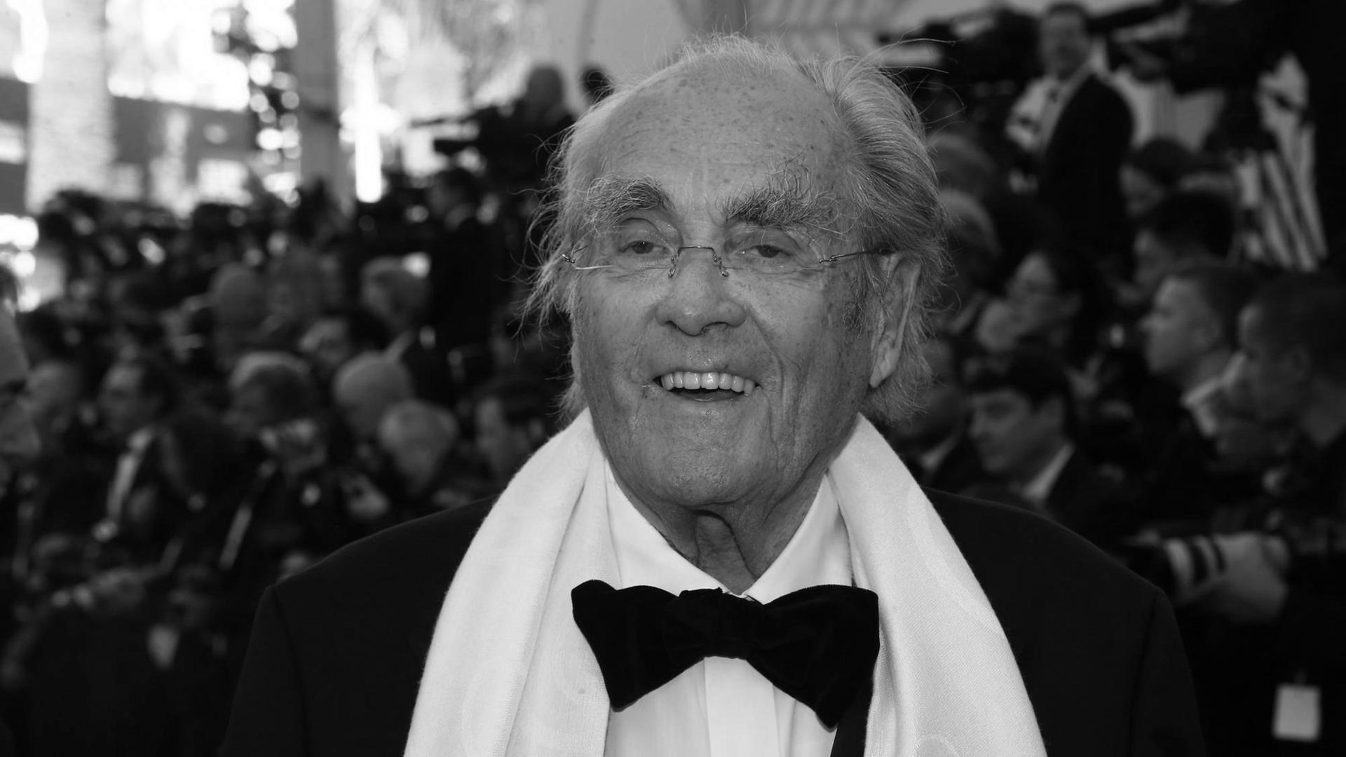 Der Komponist Michel Legrand steht in schwarzen Anzug und weißem Schal vor einer menschenmenge beim Filmfestival von Cannes 2017. Der Komponist Michel Legrand steht in schwarzen Anzug und weißem Schal vor einer menschenmenge beim Filmfestival von Cannes 2017.