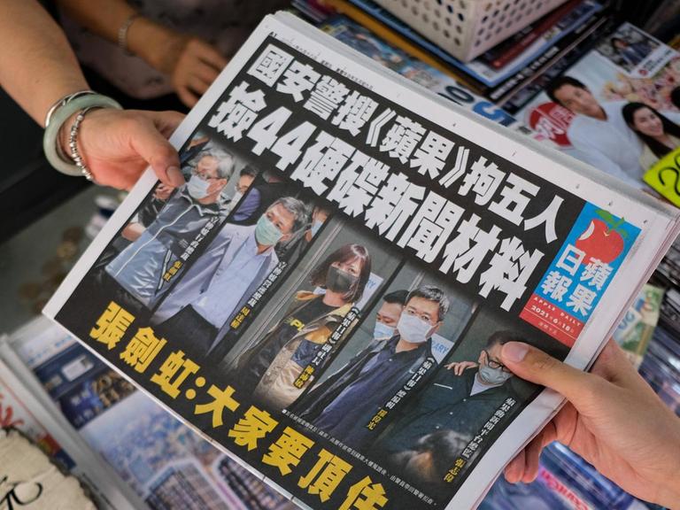 Die Hongkonger Tageszeitung Apple Daily wird an einem Kiosk von Verkäuferin zu Kundin gereicht.