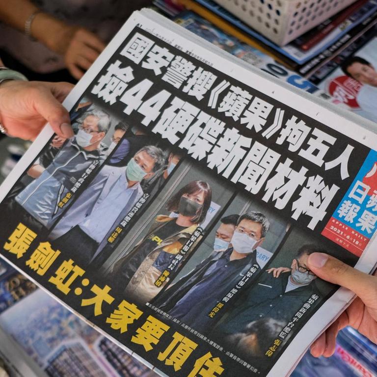 Die Hongkonger Tageszeitung Apple Daily wird an einem Kiosk von Verkäuferin zu Kundin gereicht.