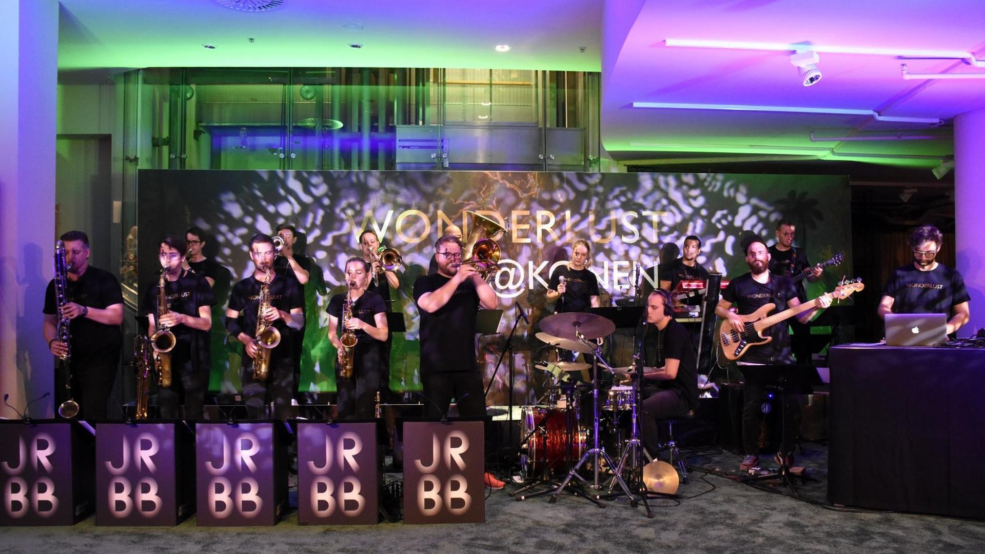 Jazzrausch Big Band auf der Bühne bei einer Veranstaltung in München. Die Band spielt, im Hintergrund grünes und violette Lichteffekte.