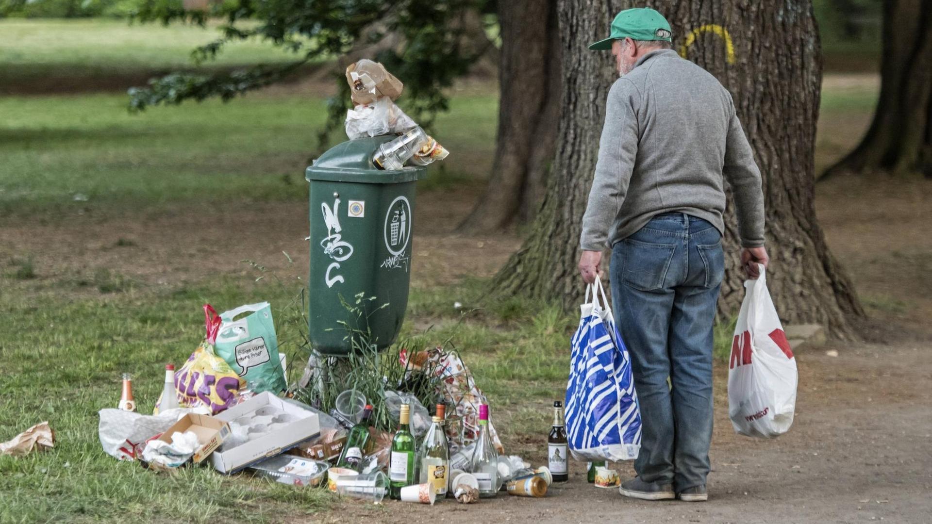 Farbfoto, ein alter Mann sammelt Flaschen vor einem städtischen Müllbehälter