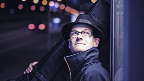Sven Faller nachts mit seinem Kontrabass, Straßenlichter im Hintergrund