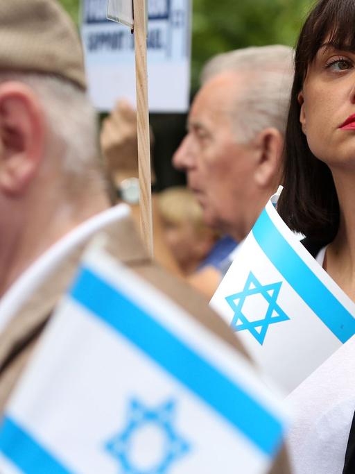 Demonstranten, die an einer Kundgebung gegen den pro-palästinensischen Al-Kuds-Tag in Berlin teilnehmen, halten kleine israelische Flaggen in den Händen.