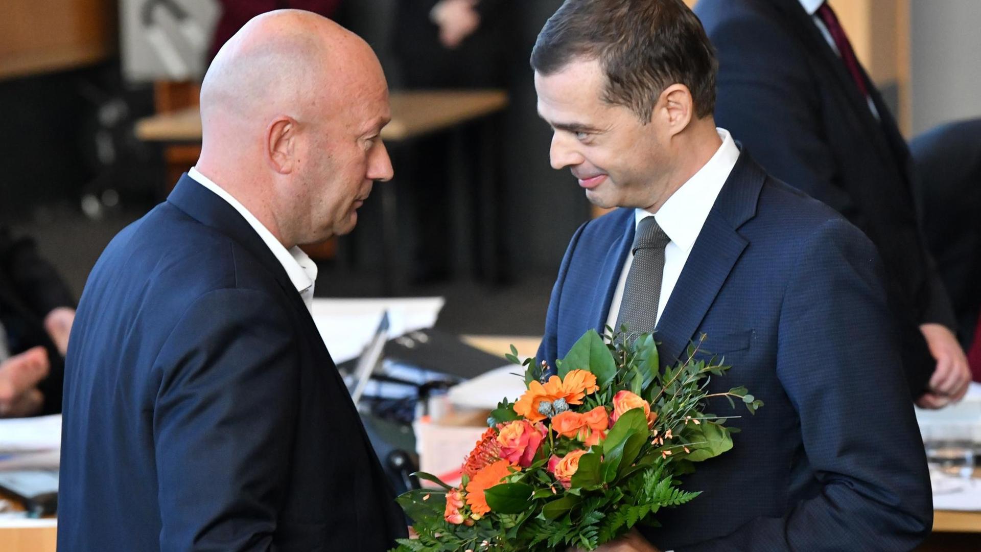 Mike Mohring, CDU-Fraktionschef, gratuliert Thomas Kemmerich (FDP), dem neuen Thüringer Ministerpräsidenten, mit einem Blumenstrauß.