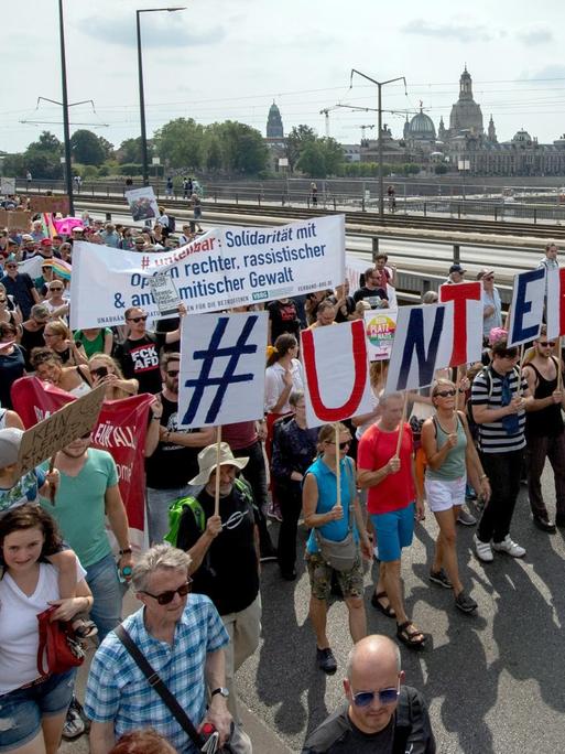 Anhänger des Bündnisses #unteilbar gehen während einer Demonstration über die Carolabrücke vor der historischen Altstadtkulisse von Dresden.