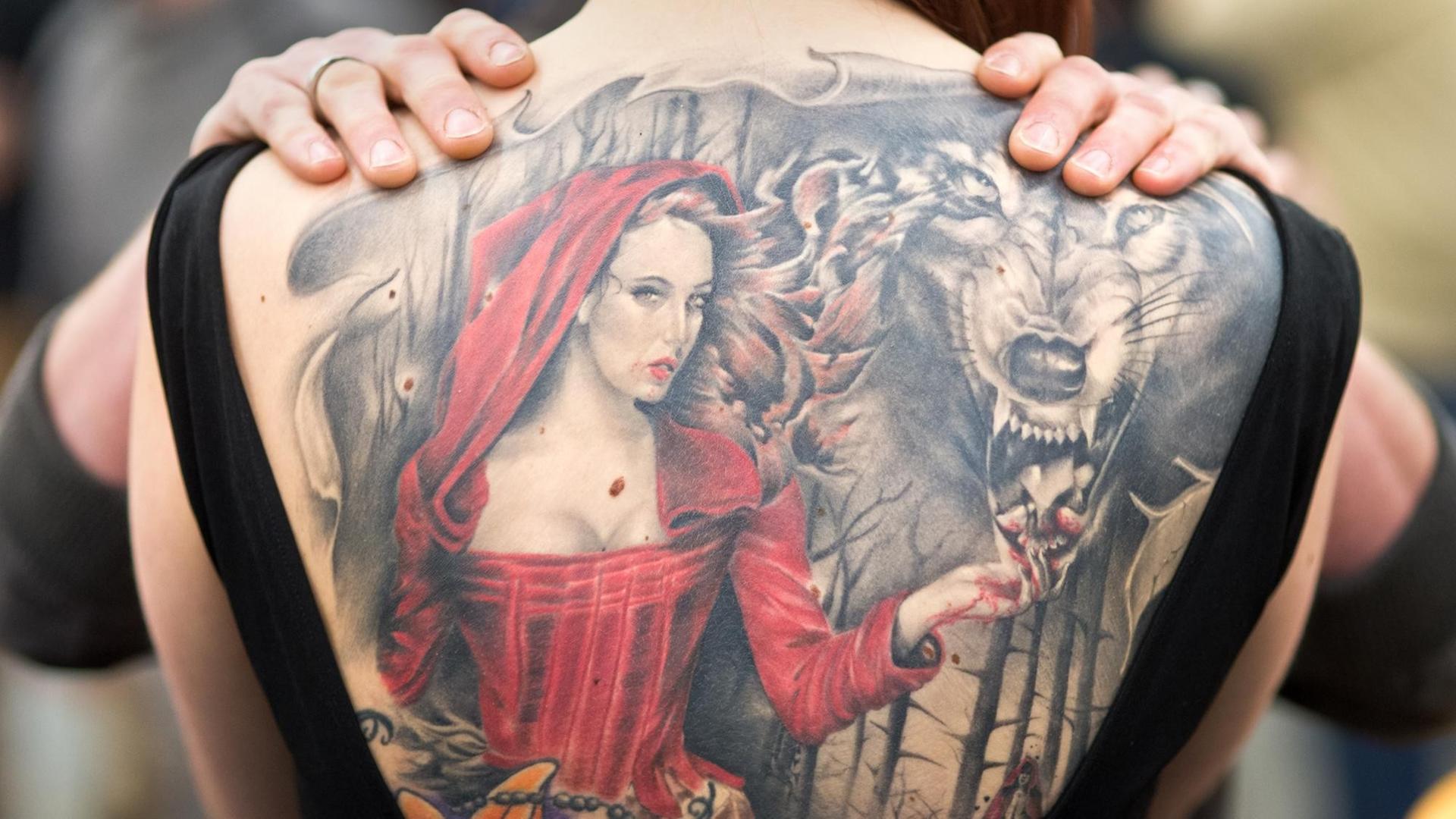 Das Foto zeigt eine Tätowierung - eine Frau trägt ein Bild von Rotkäppchen und dem bösen Wolf auf dem Rücken.