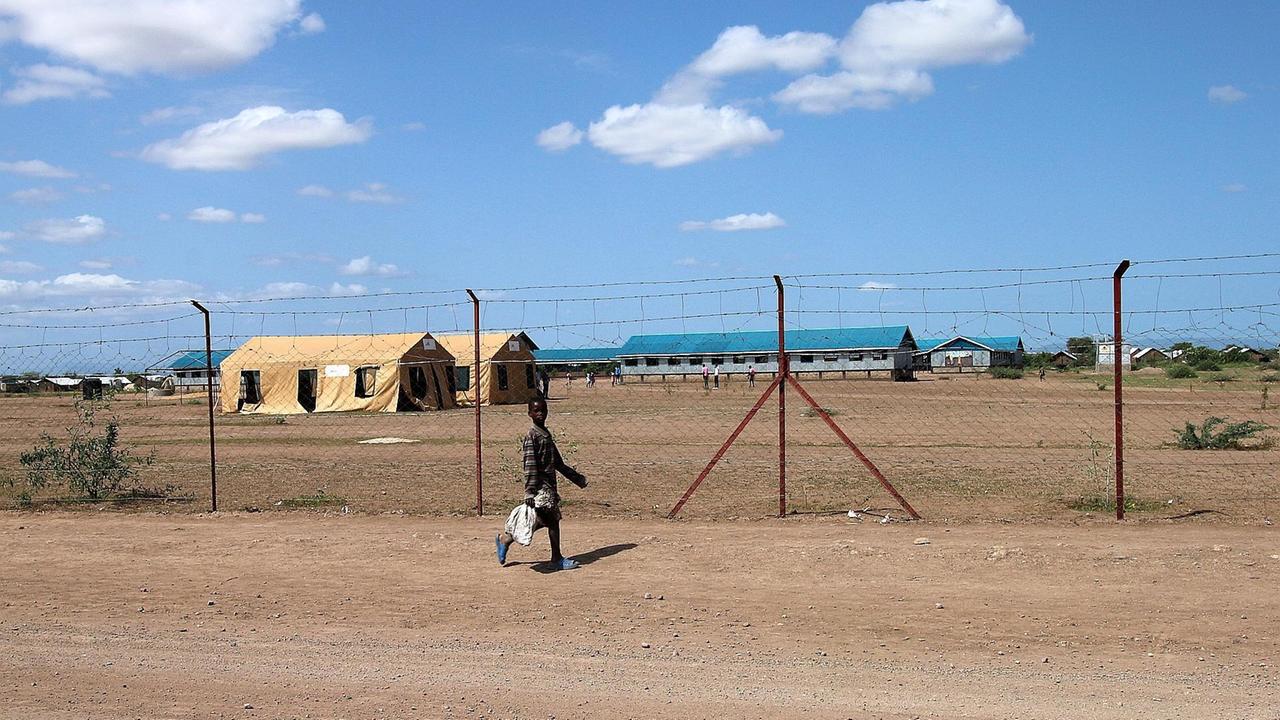 Ein Kind läuft vor einem Zaun der Flüchtlingsunterkunft.
