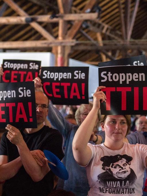 Kirchentagsteilnehmer halten bei einem Flashmob im Vorfeld einer Veranstaltung im Programm des deutschen evangelischen Kirchentags Schilder mit der Aufschrift "Stoppen Sie CETA!" und "Stoppen Sie TTIP"